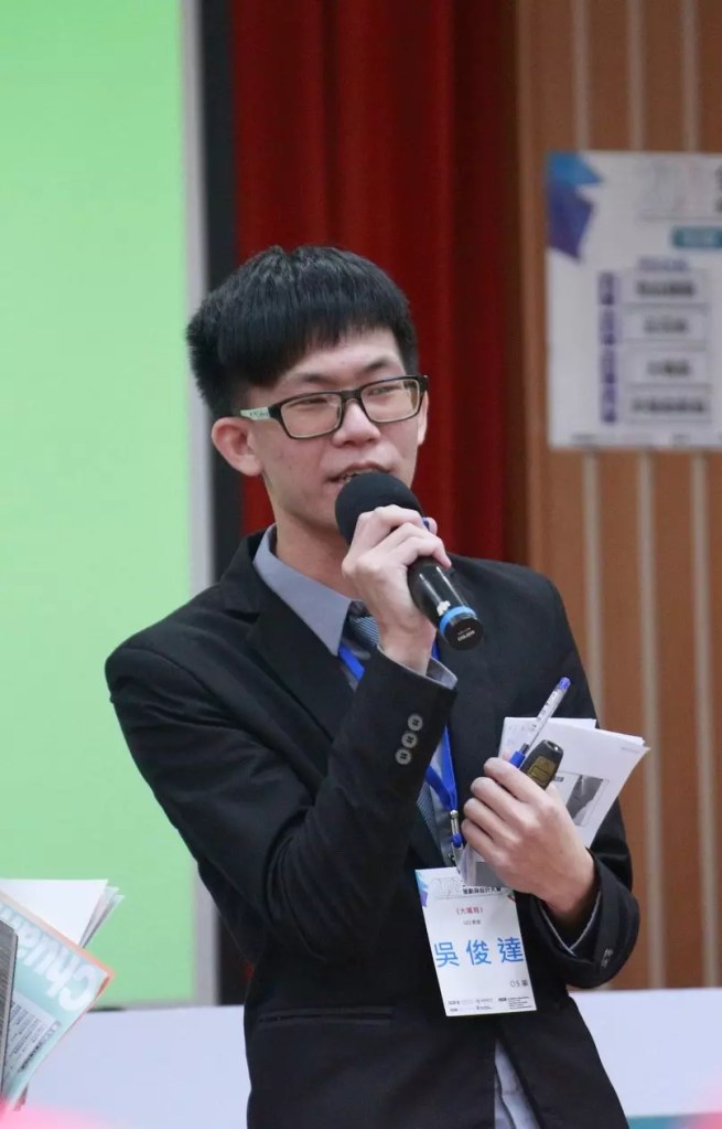 一位帶著眼鏡的男生拿著麥克風正在講解